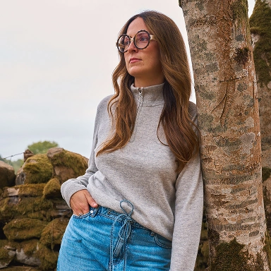 Frau trägt einen grauen Pullover und eine blaue Jeans im Freien