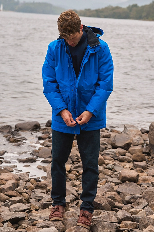 Man wearing a waterproof rain jacket and trousers by a lake